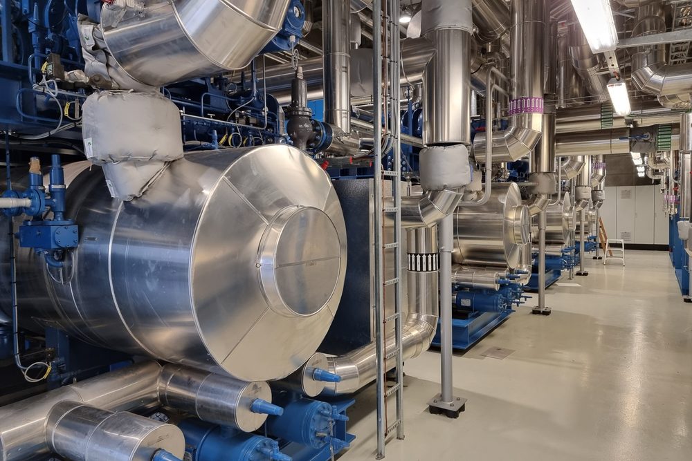 A large heat pump and insulated pipework inside an energy centre.